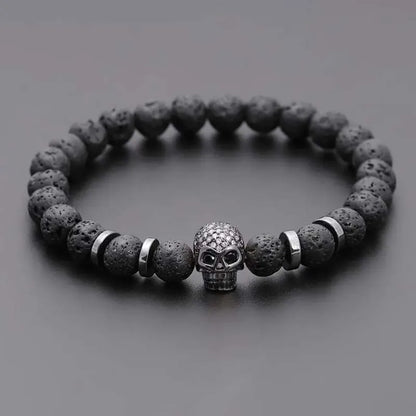 Bracelet with dark beads and a skull charm on a gray background