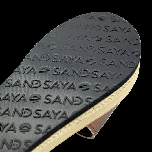 Close-up of a sandal sole with 'SAND SAYA' branding on a white background