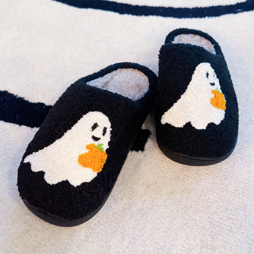 Black slippers with ghost and pumpkin design on a striped fabric background