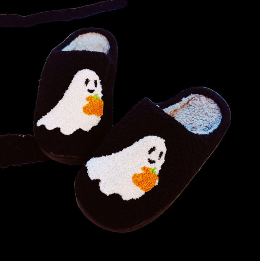 Pair of black slippers with ghost and pumpkin design on a white background
