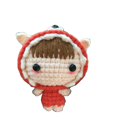 Crocheted doll with red hood and scarf on a tree branch with green leaves in the background