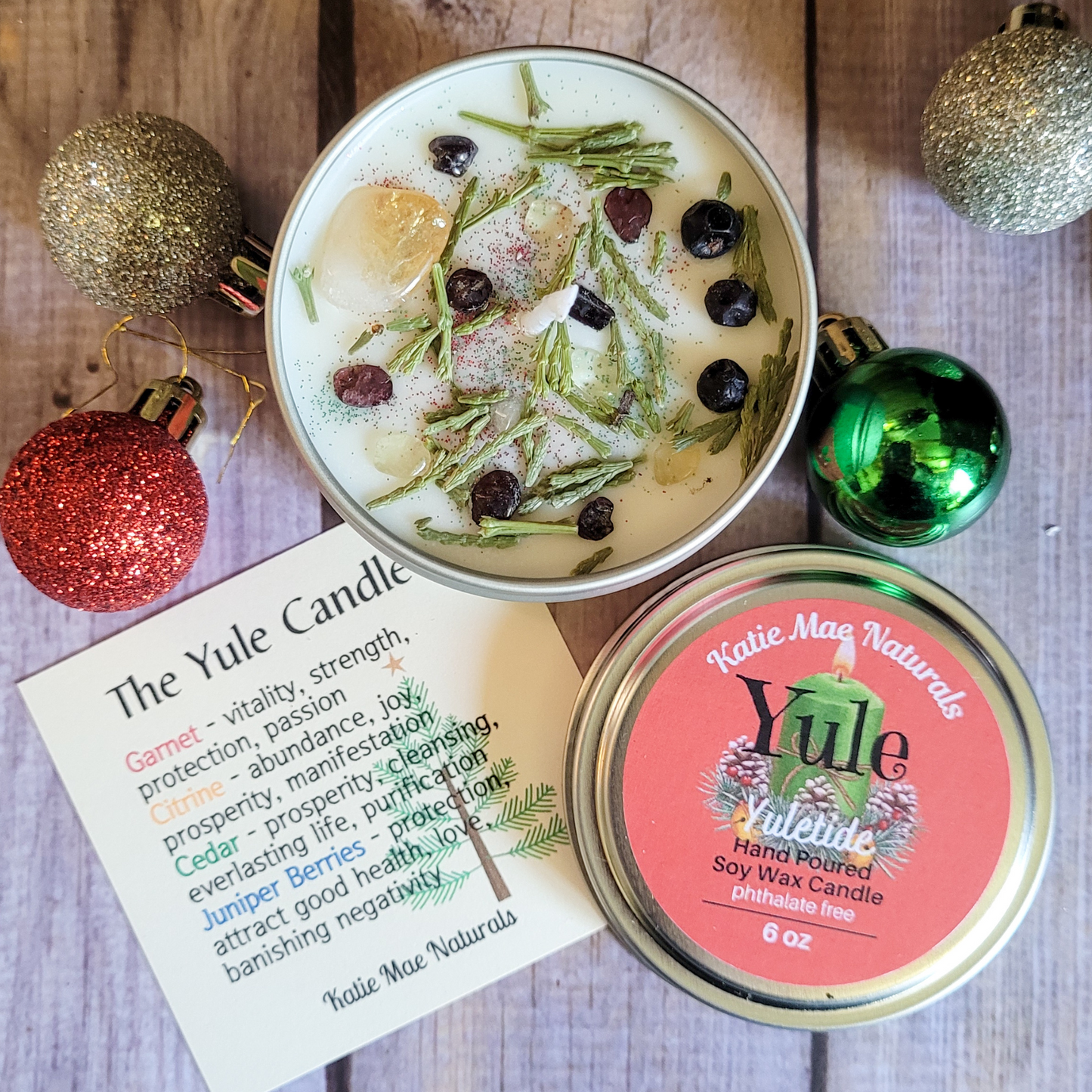 Katie Mac Naturals Yule candle with decorative ornaments on a wooden surface