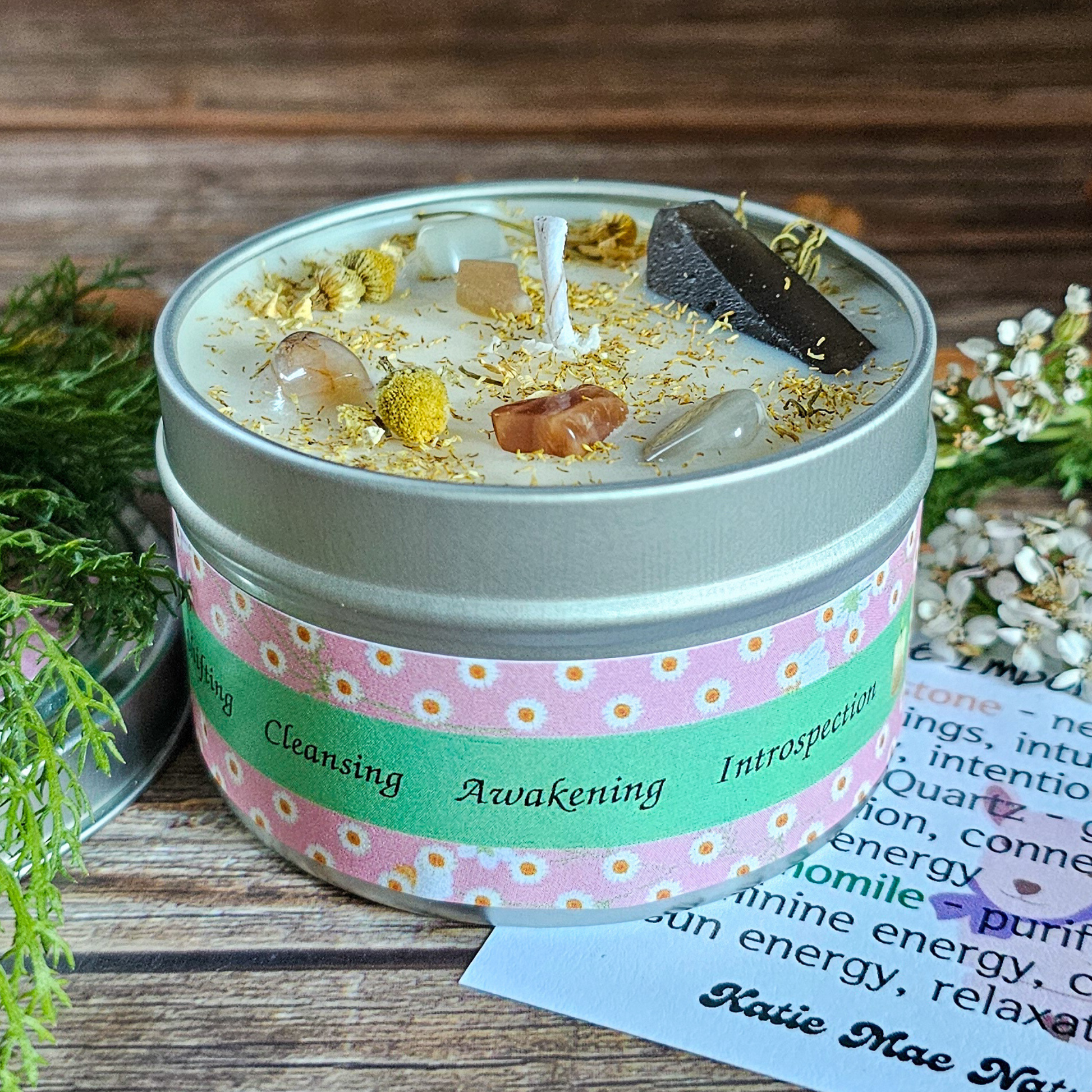 Candle in a tin with decorative elements on a wooden surface