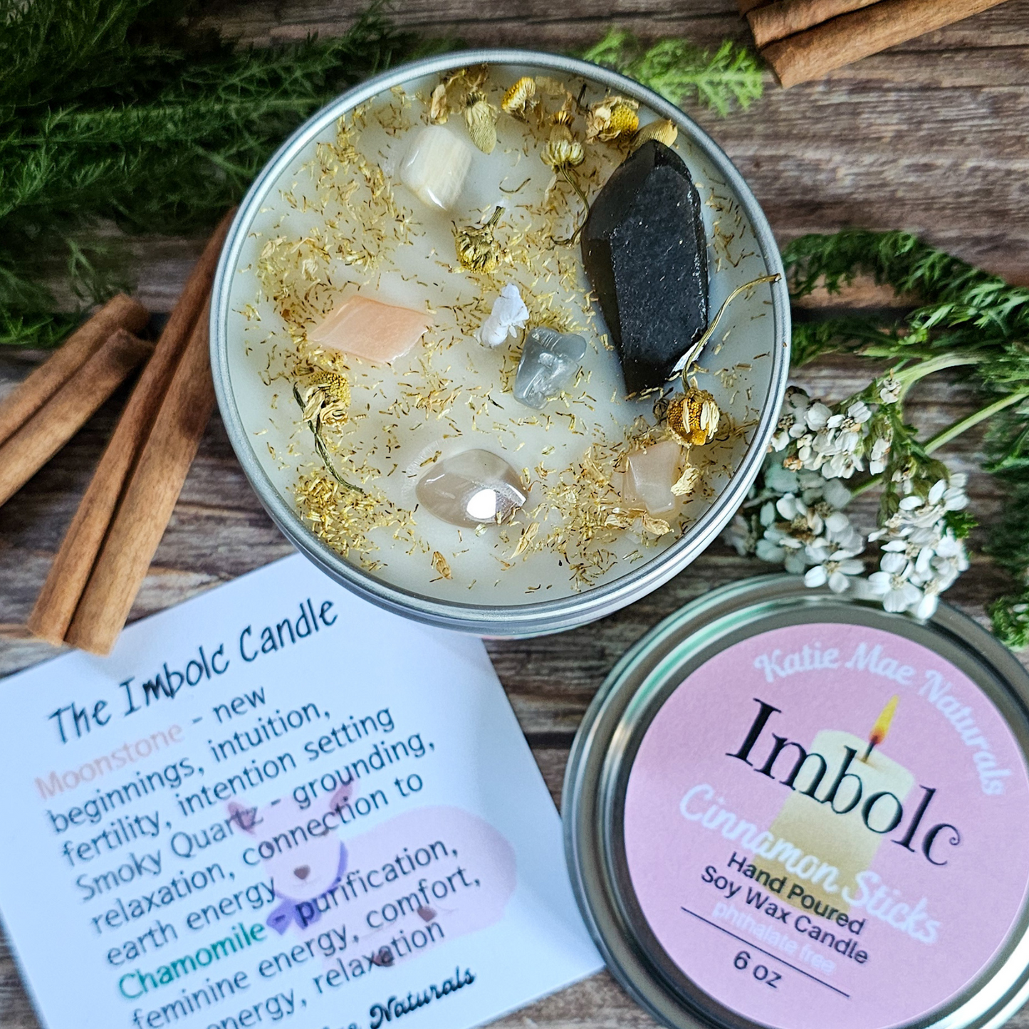 Candle with decorative elements on a wooden surface with a label and additional candles.