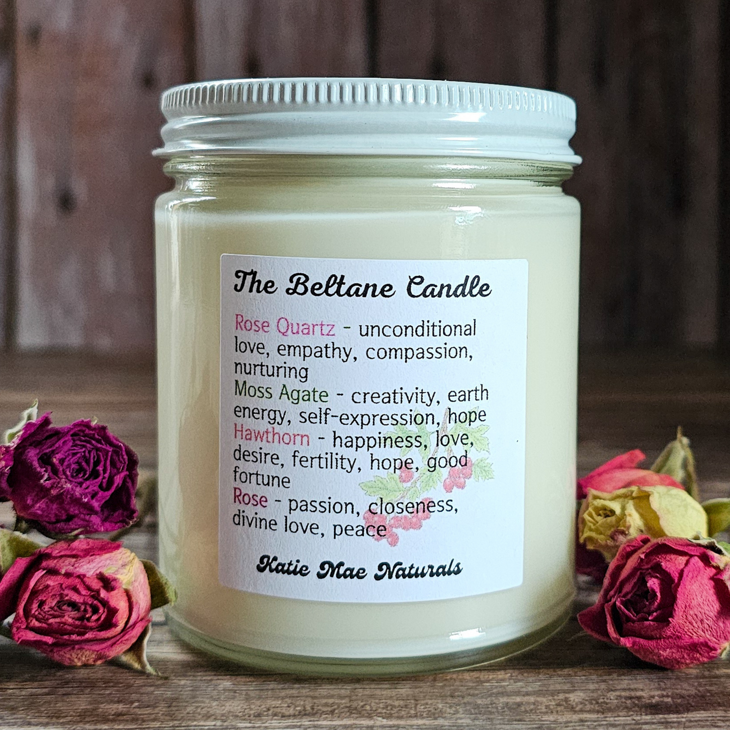 Candle jar with a label surrounded by flowers on a wooden surface