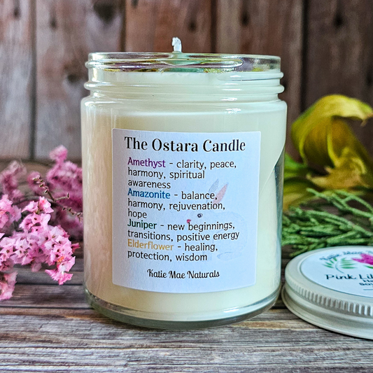 Ostara candle with label on a wooden surface with flowers in the background