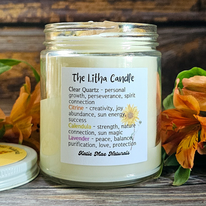 Candle in a glass jar with a label on a wooden surface surrounded by flowers