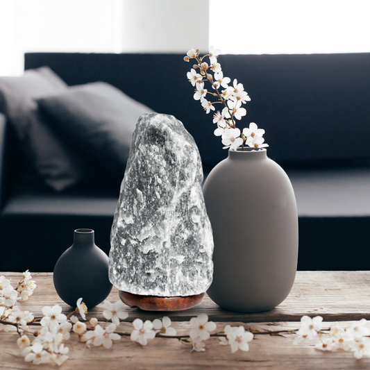 Decorative vases and a lamp on a wooden table with flowers in the foreground