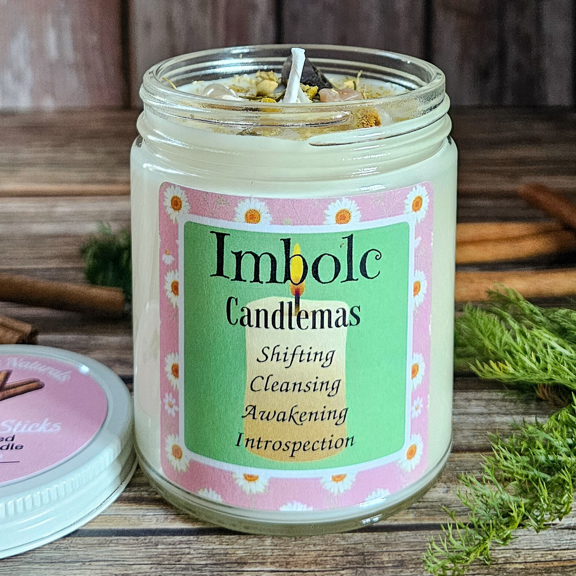 Candle in a jar with 'Imbolc Candlemas' label on a wooden surface