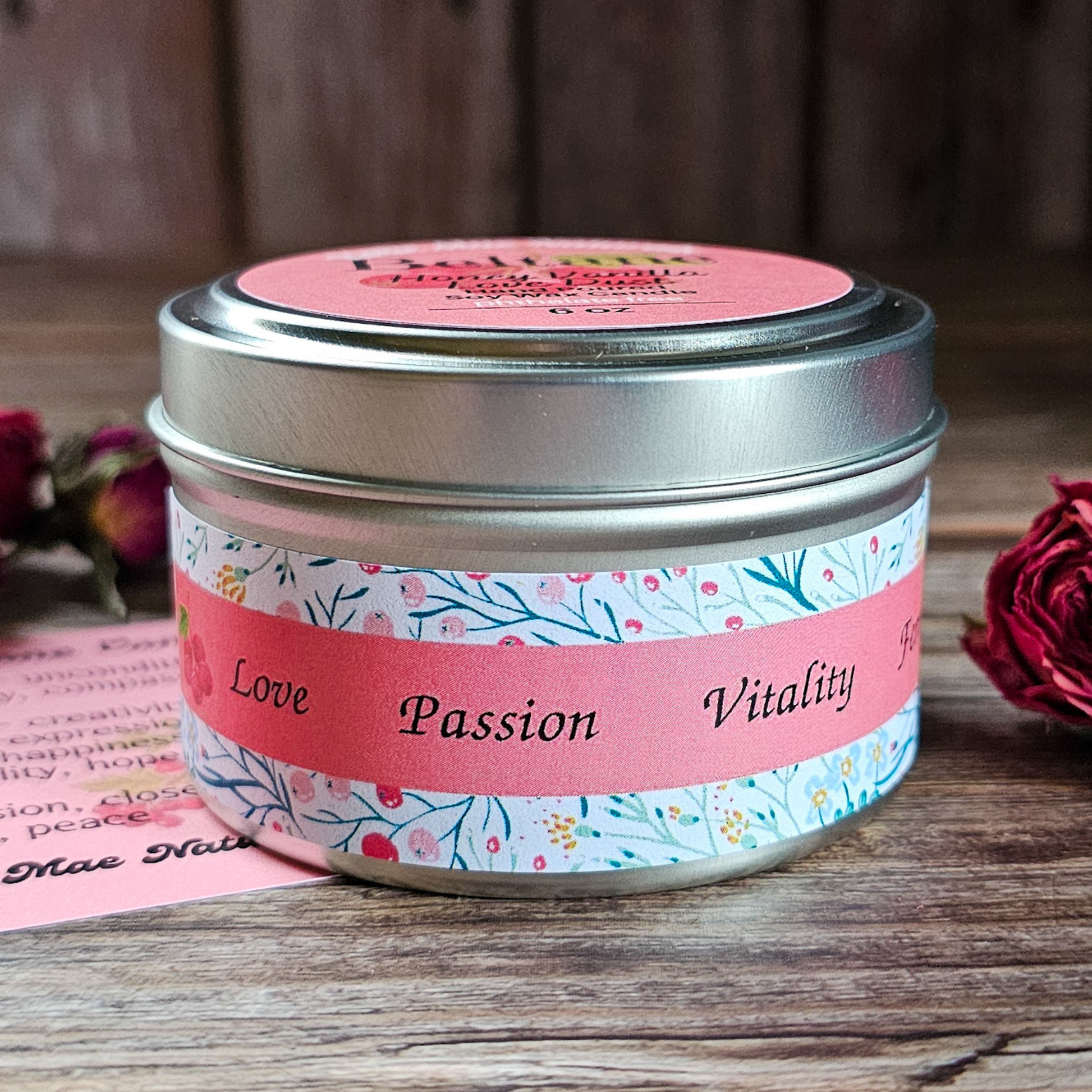 Candle tin with floral label and pink lid on a wooden surface