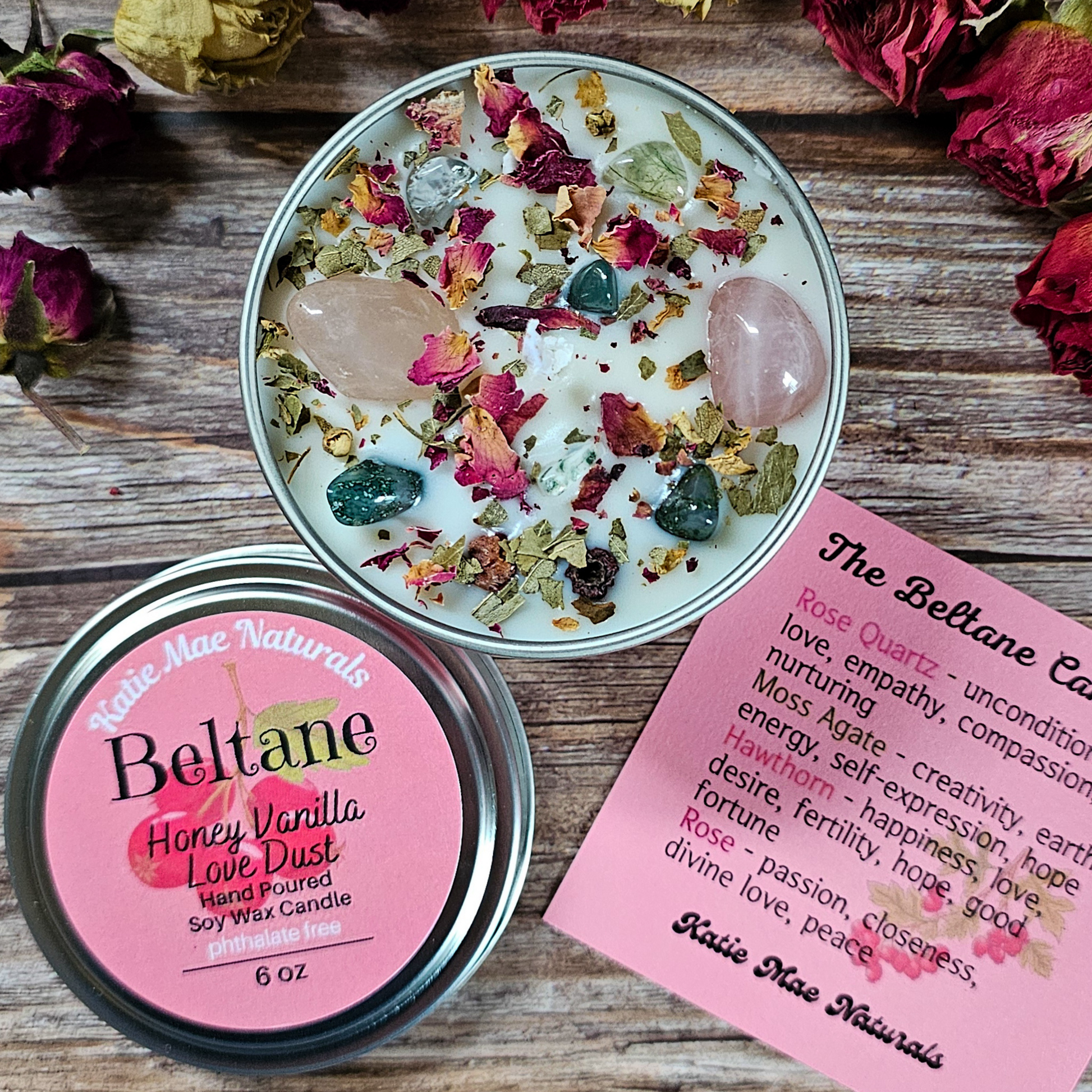 Candle with rose quartz and crystals on a wooden surface with a label and information sheet.
