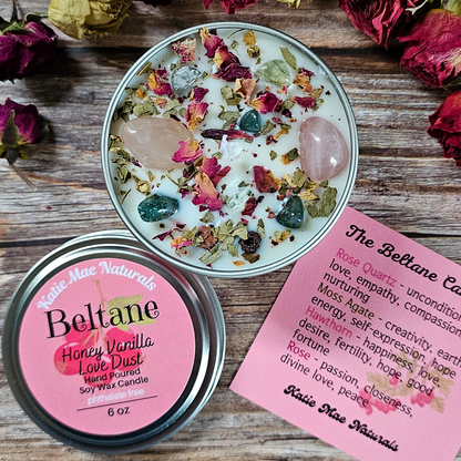 Candle with rose quartz and crystals on a wooden surface with a label and information sheet.