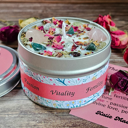 Candle in a decorative tin with floral elements and text on a wooden surface.
