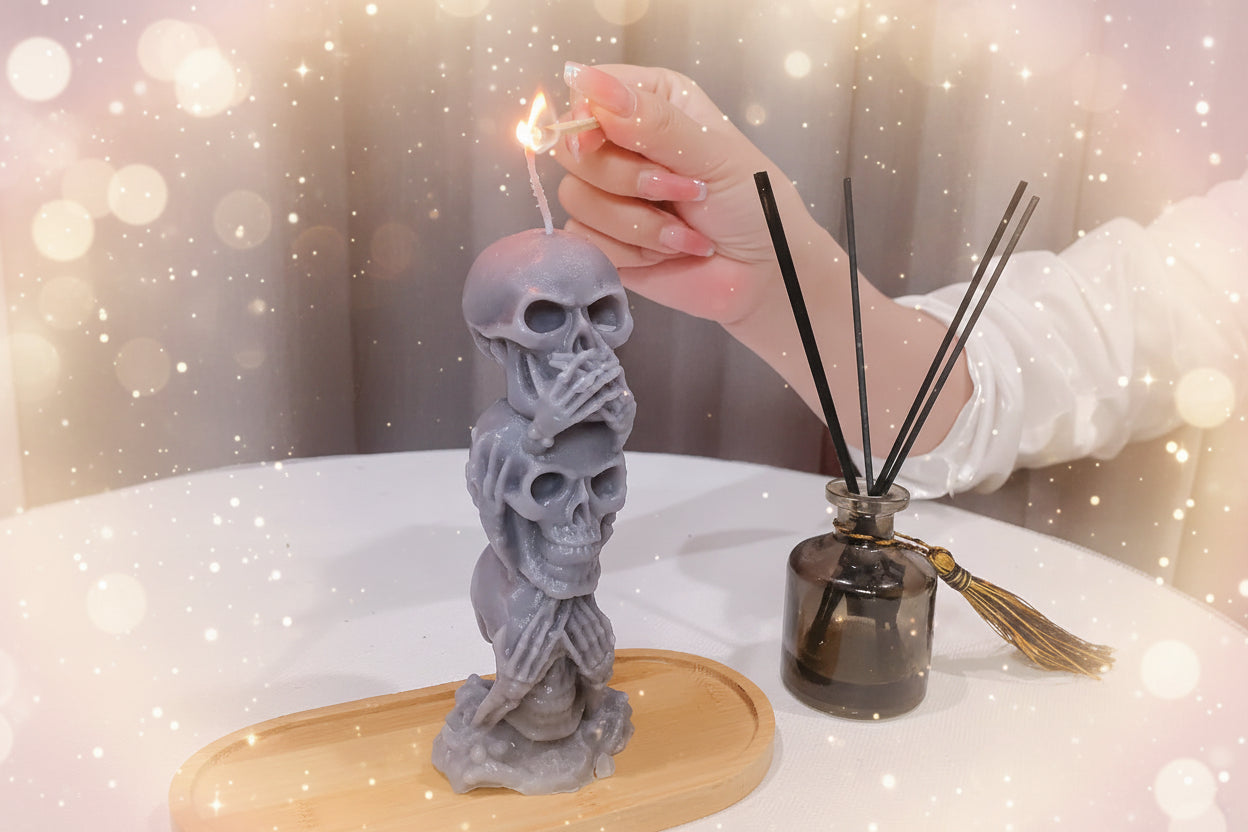 Hand lighting a skull-shaped candle with a diffuser in the background