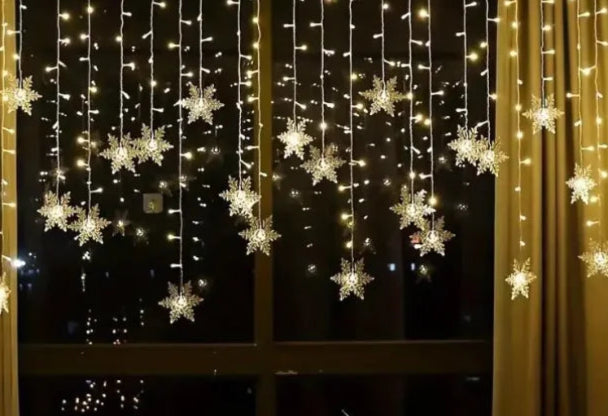 Decorative string lights with snowflake ornaments on a window, creating a cozy indoor setting.