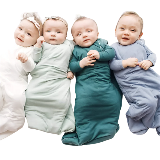 Four babies wrapped in colorful swaddles lying on a white surface