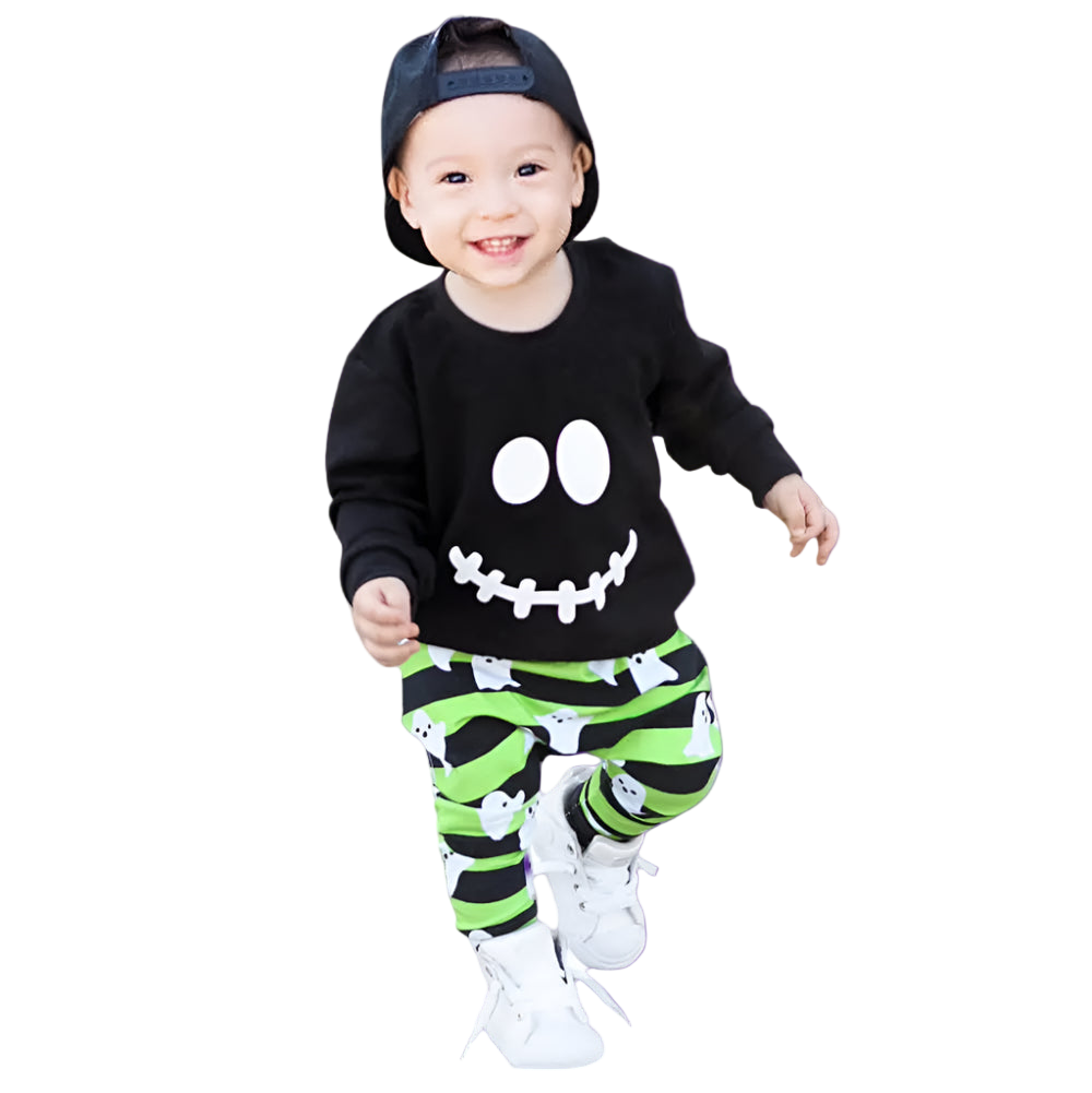 Child wearing a black shirt with a smiley face and green striped pants on a white background
