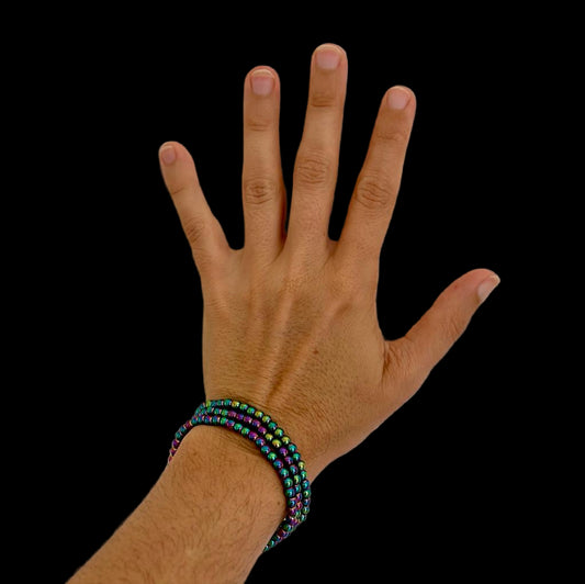 Hand wearing a colorful beaded bracelet on a plain background