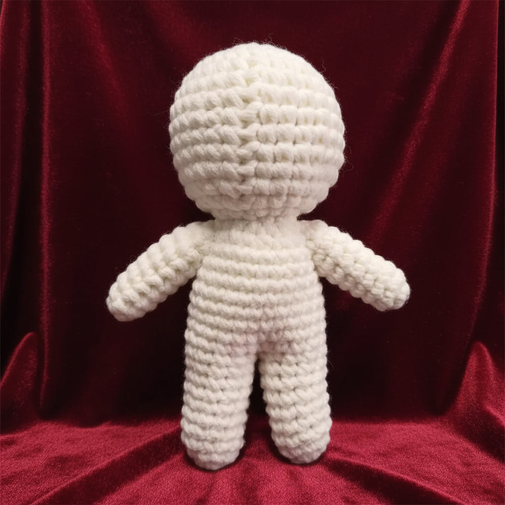 White knitted doll on a gray surface with a blurred background