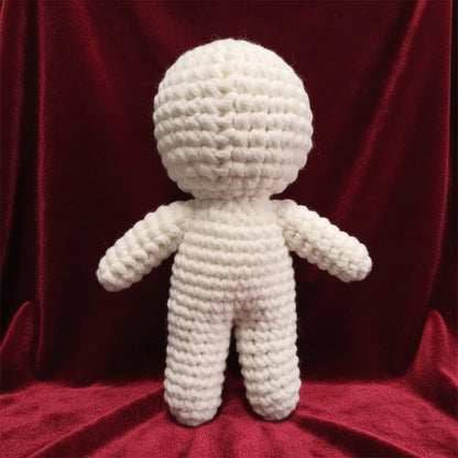 White knitted doll on a gray surface with a blurred background