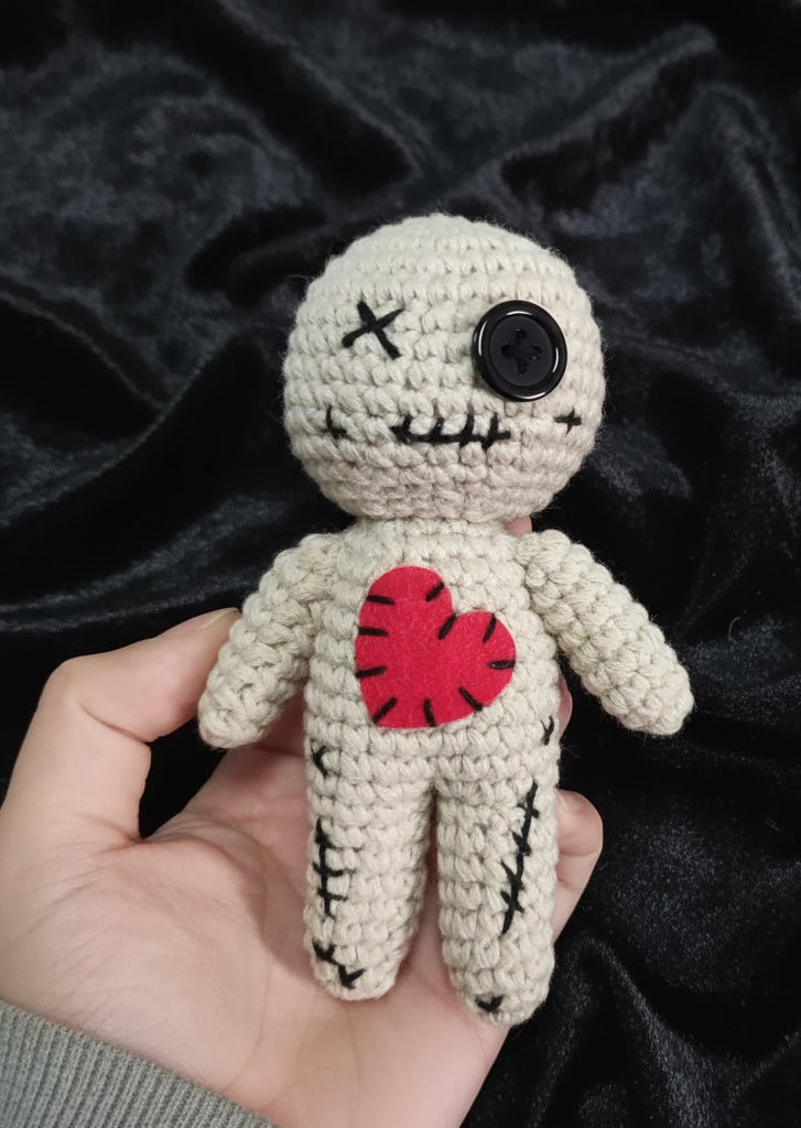 Handmade crochet doll with a red heart on a neutral background