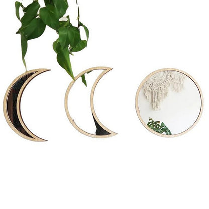 Two decorative wall hangings shaped like crescent moons and a round mirror with a plant in the background.