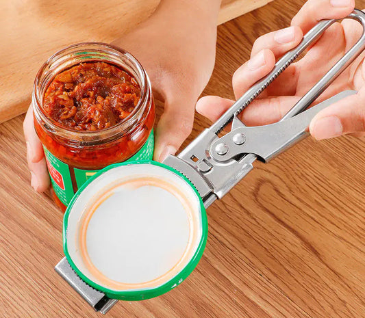 Person using a can opener on a jar of red paste on a wooden surface
