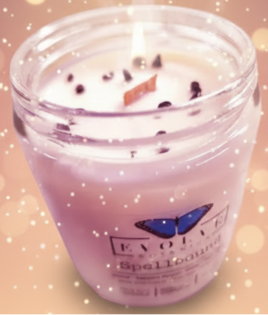 Candle in a glass jar with 'Evolve Botanicals' label on a marble surface