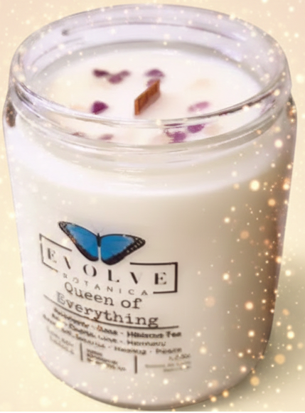 Candle in a glass jar with 'Evolve Botanica' label on a pink background
