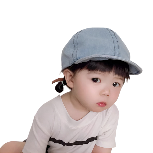 Child wearing a denim cap against a plain background
