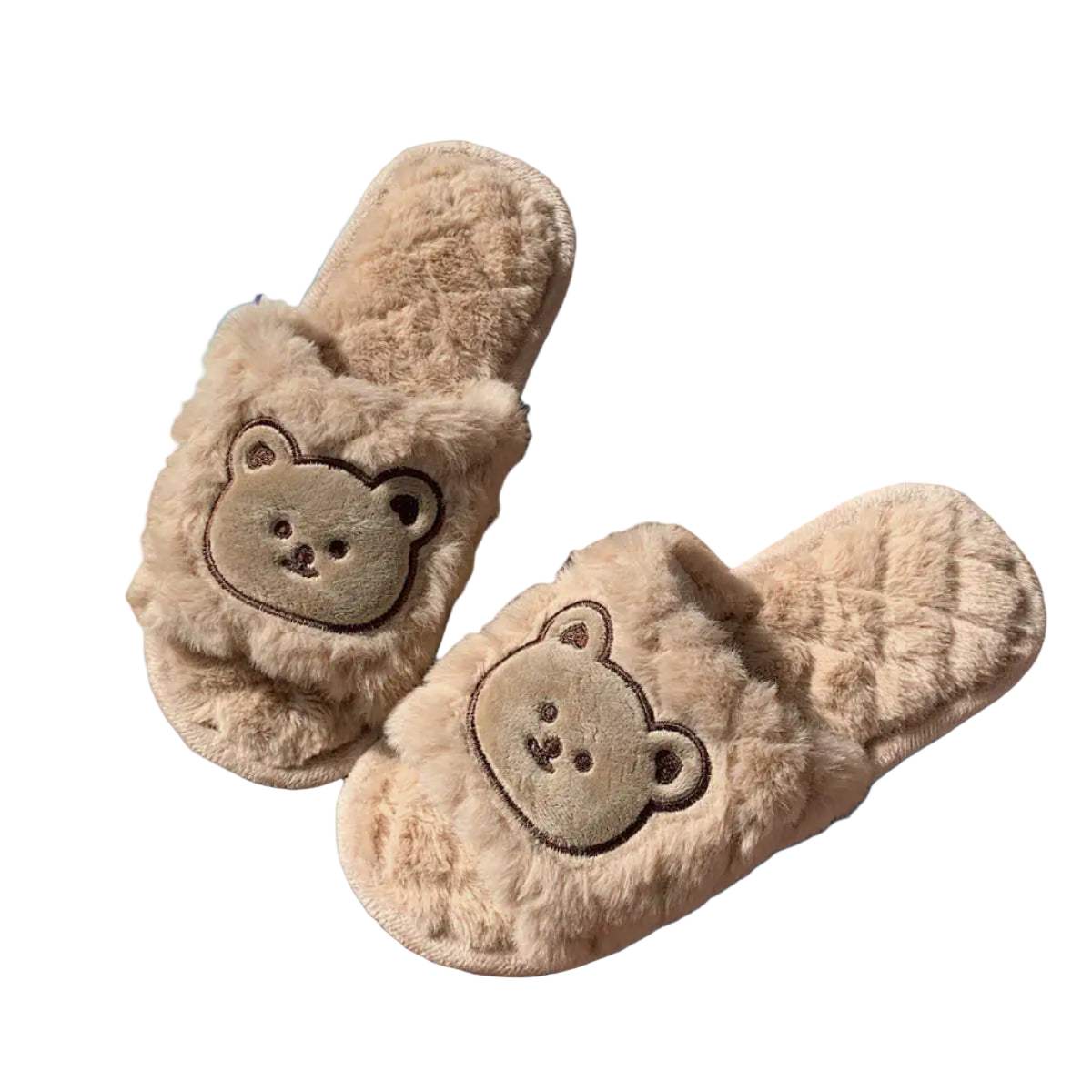 Pair of fluffy slippers with bear face design on a wooden surface