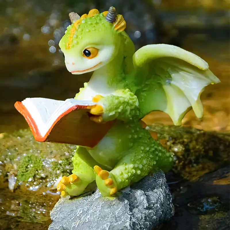 Toy dragon reading a book on a rock with a natural background