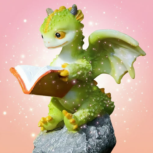 Toy dragon reading a book on a rock with a natural background