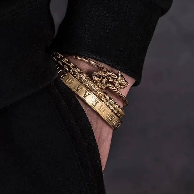 Gold bracelets on a person's wrist with a dark background