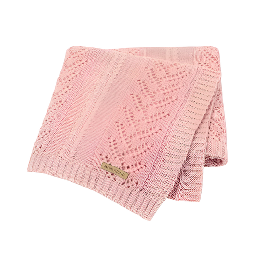 Pink knitted blanket with a brand label on a white background