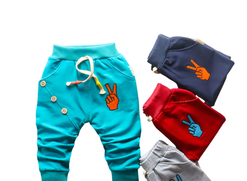 Colorful children's pants with peace sign designs on a woven mat.