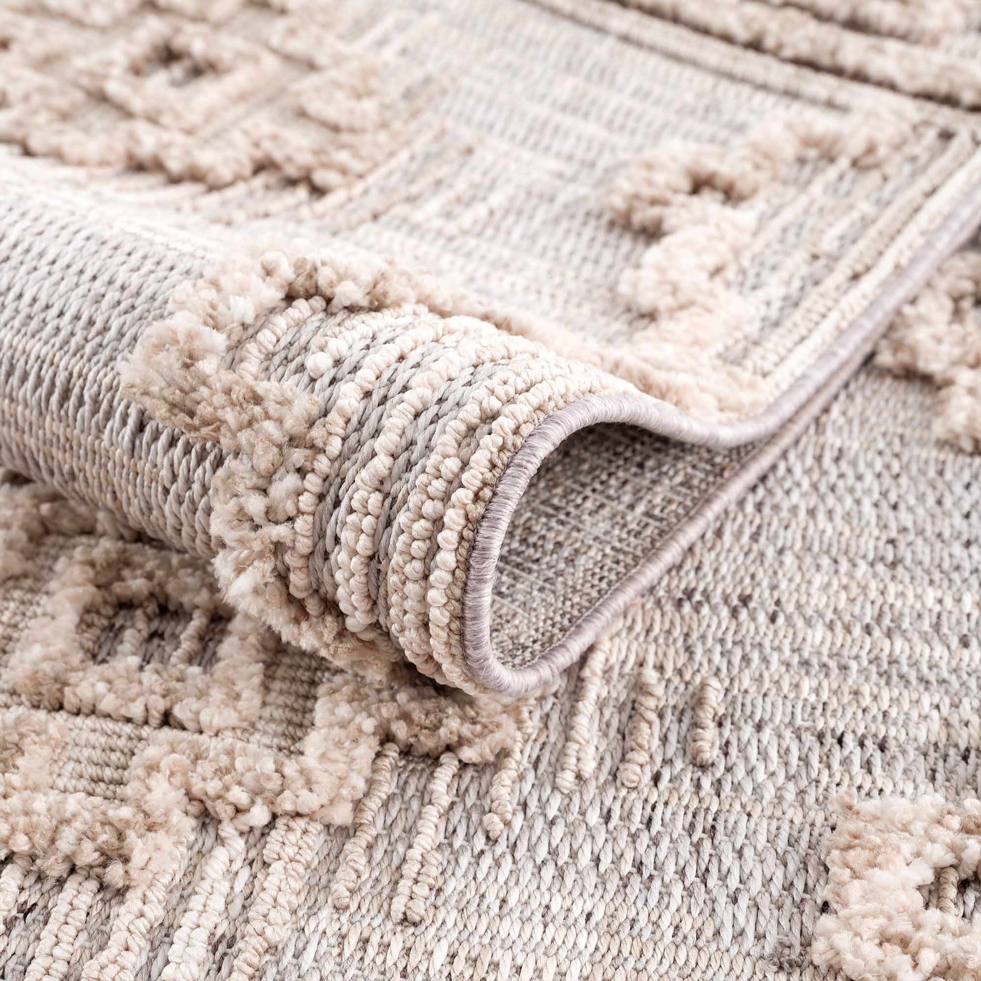 Close-up of a beige textured rug with a rolled-up section.