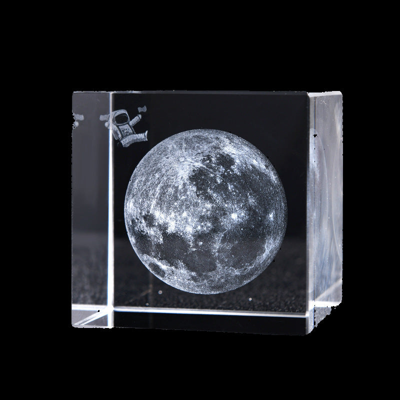 Crystal block with moon engraving and astronaut icon on a black background