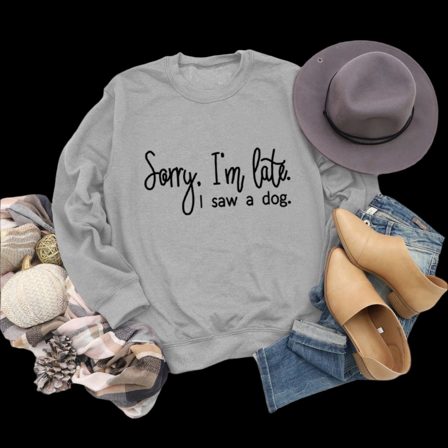 Gray sweatshirt with text, hat, boots, and jeans on a wooden surface