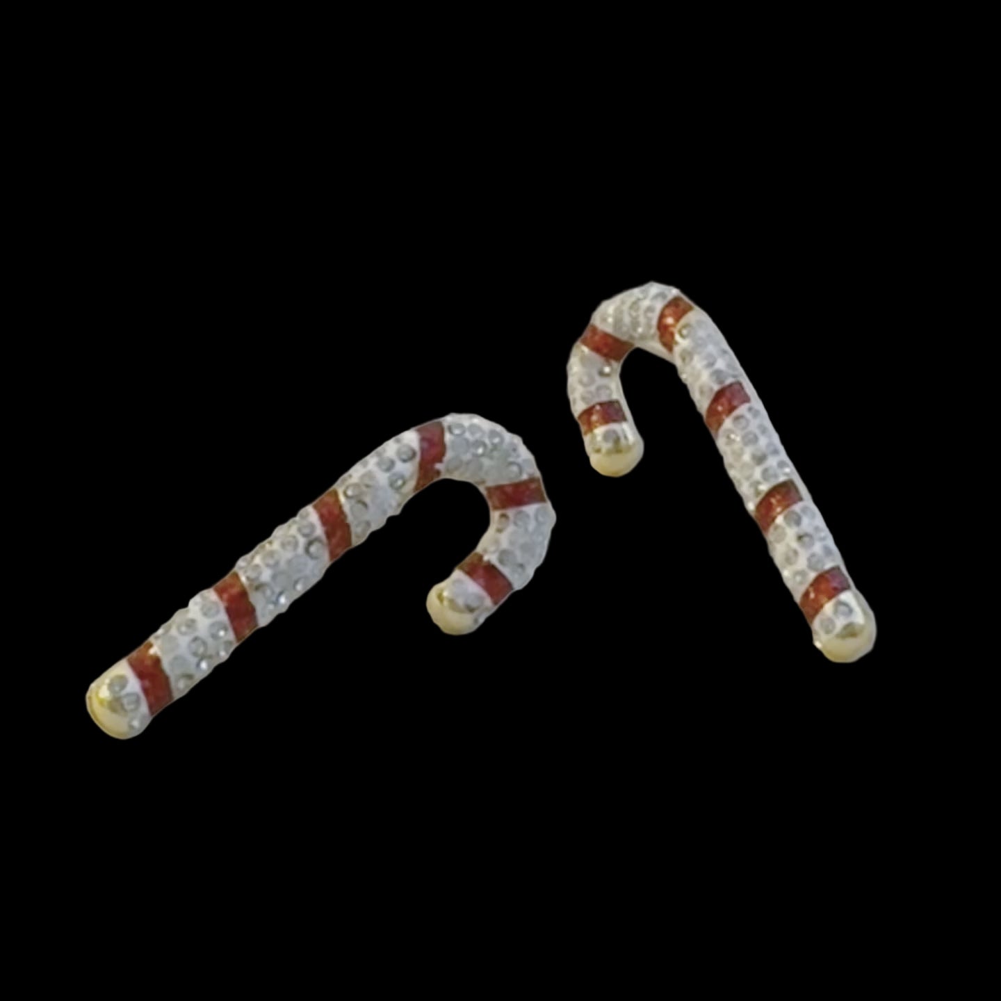 Candy cane-shaped earrings with red and white design on a light gray background