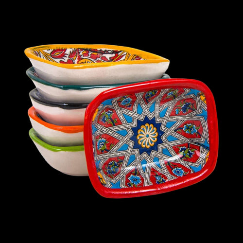 Stack of colorful ceramic trays with intricate designs on a light gray background