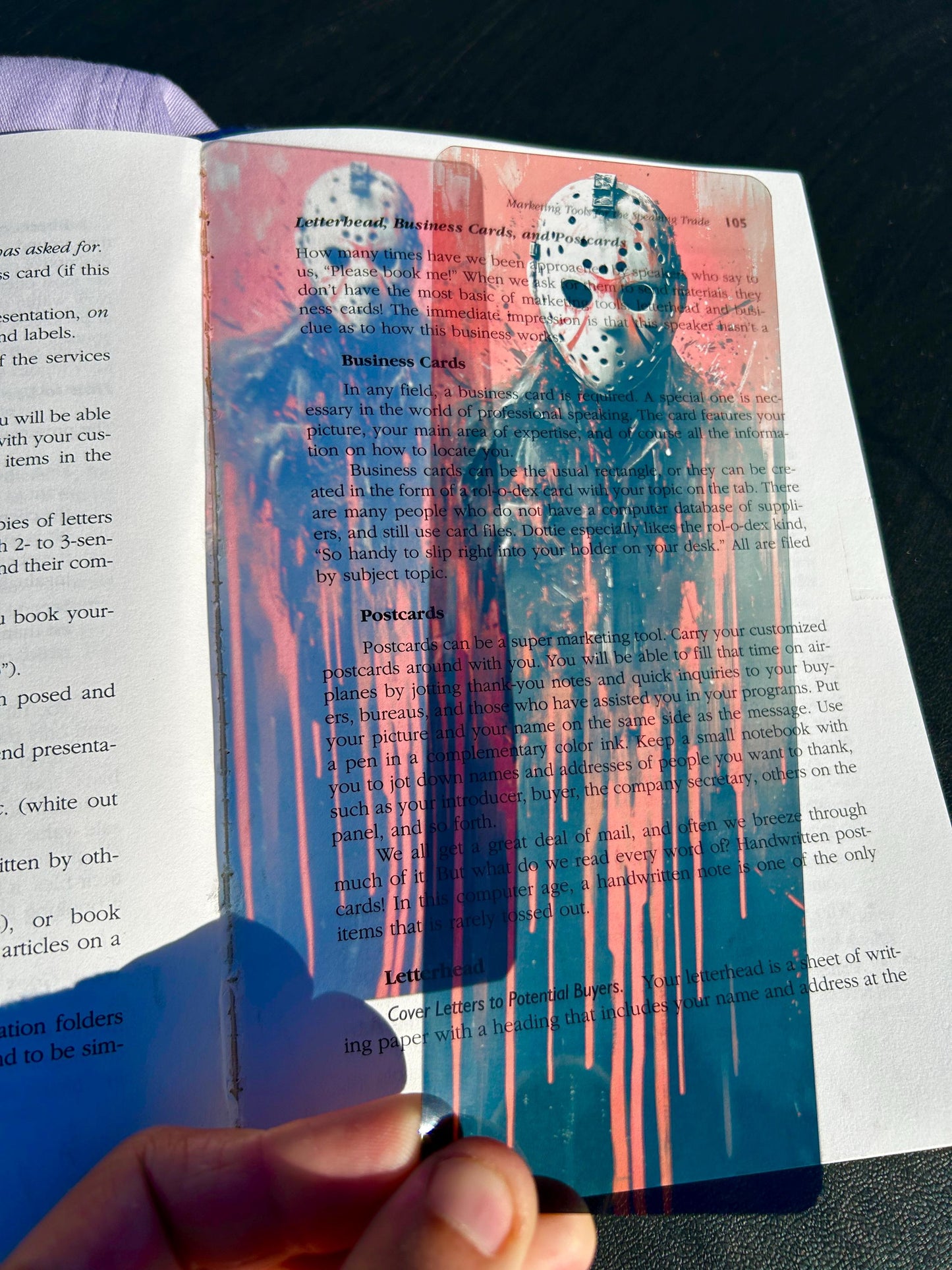 Card with a blue and red design featuring a face held over an open book.