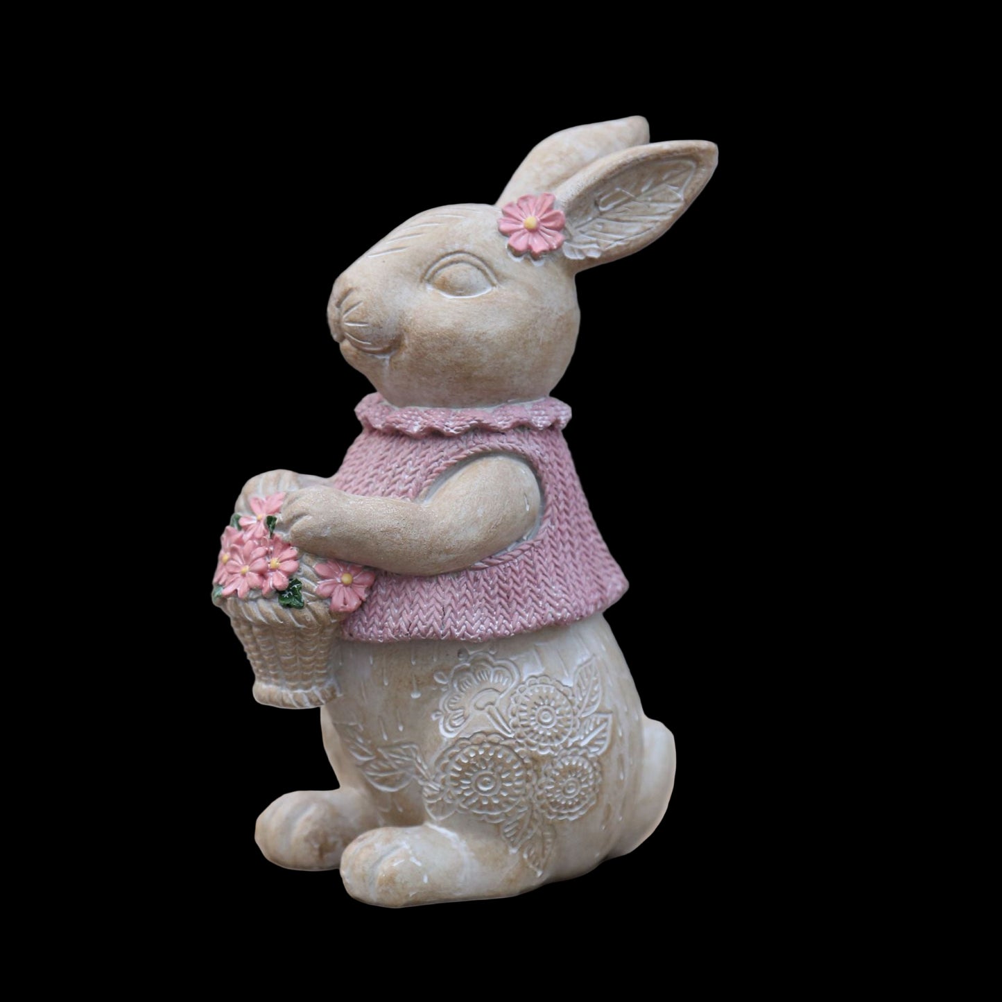 Decorative rabbit figurine wearing a pink sweater and holding flowers on a stone surface.