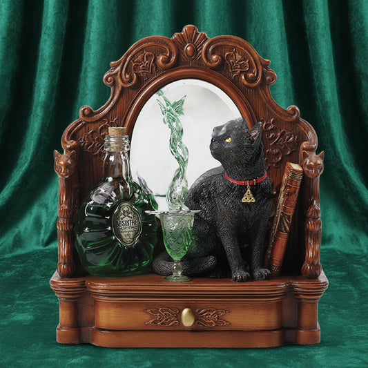 A decorative gothic-style wooden cabinet or shelf display featuring an ornate carved brown wood frame with a mirror, a black cat figurine wearing a red collar, a green glass goblet, a green bottle, and a stack of vintage books, shown on a white background.
