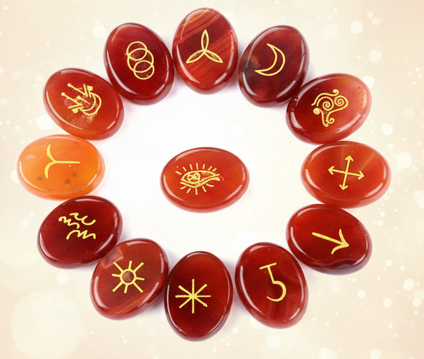 Red stones with yellow astrological symbols arranged in a circle on a white background
