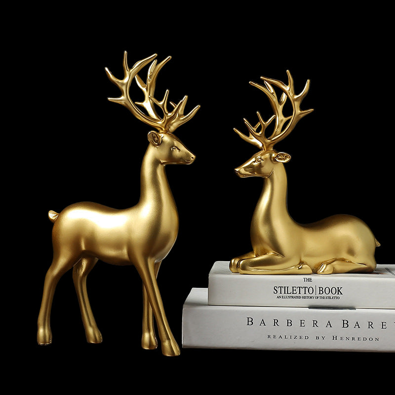 Two gold deer figurines on books with a dark background