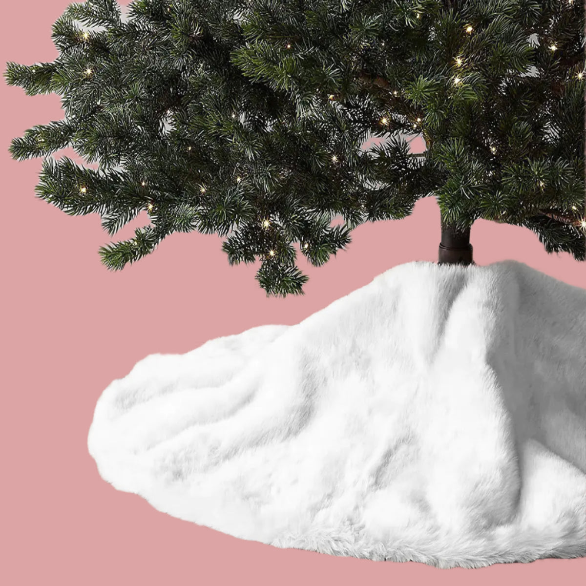 White fur tree skirt on a wooden floor with a decorated Christmas tree in the background.