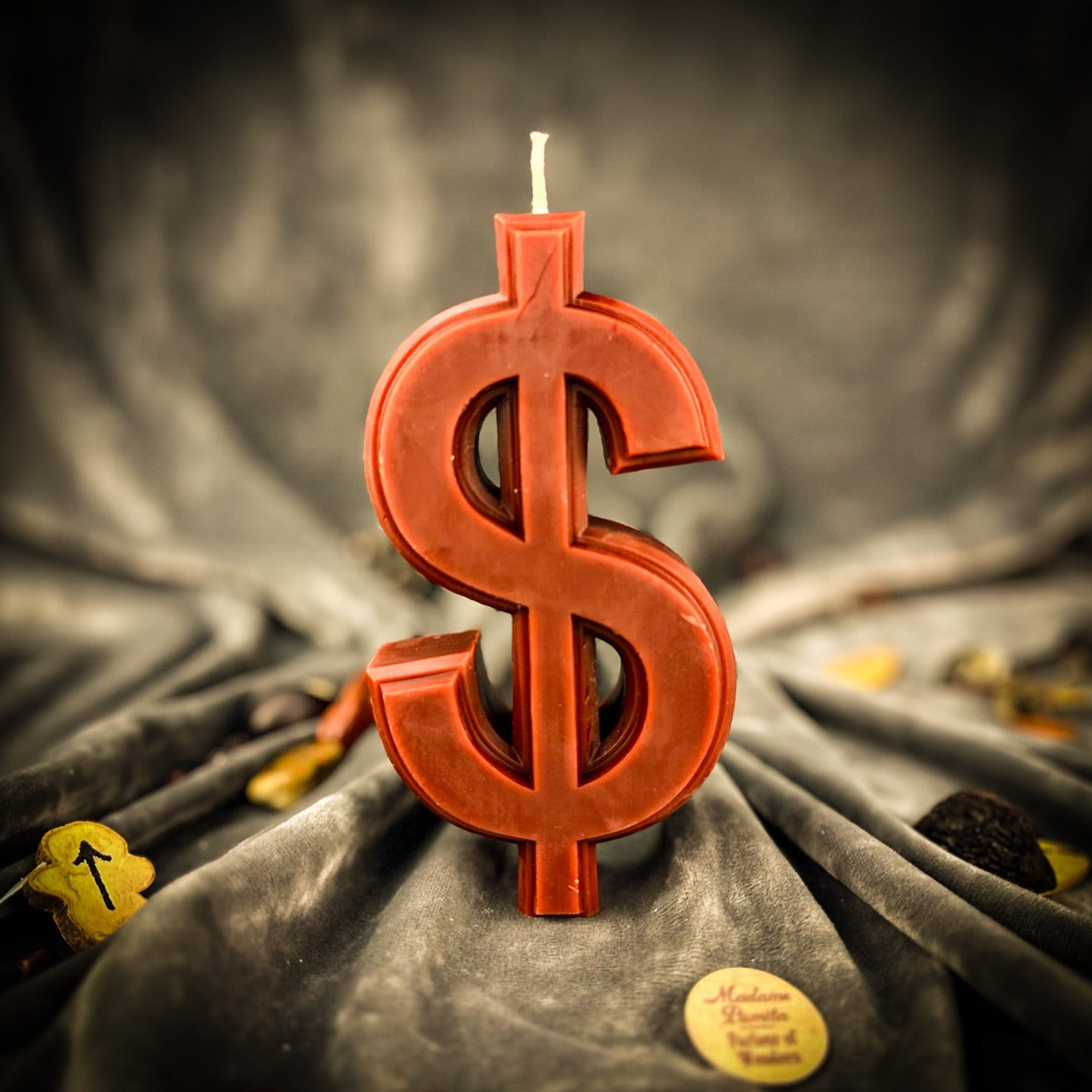 Red dollar sign candle on a textured gray fabric background
