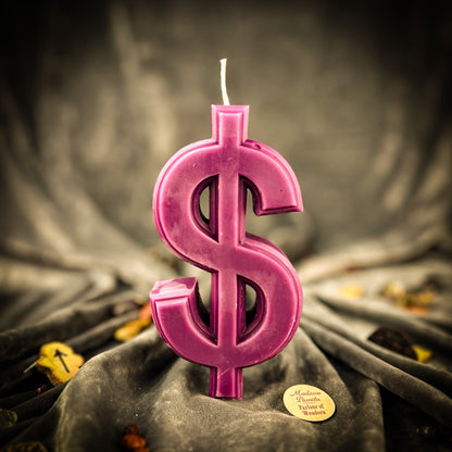 Pink dollar sign candle on a textured surface with a blurred background