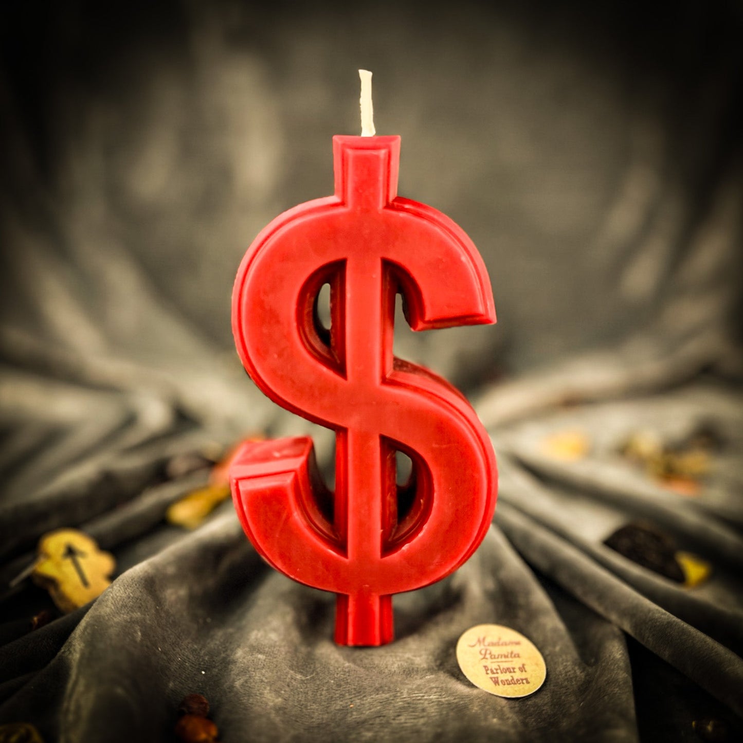 Red dollar sign candle on a dark fabric background